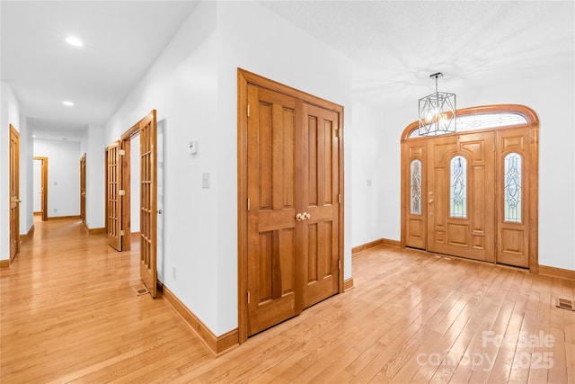 foyer entrance featuring light wood-type flooring and a notable chandelier