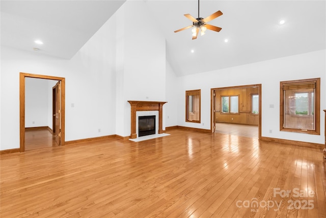 unfurnished living room featuring light wood-type flooring, ceiling fan, high vaulted ceiling, and a fireplace