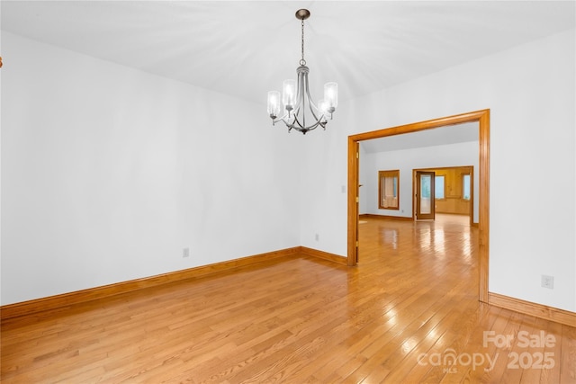 spare room with light wood-type flooring and a notable chandelier