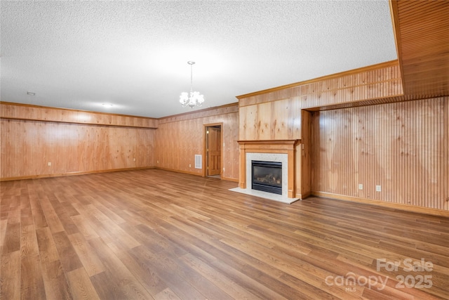 unfurnished living room featuring hardwood / wood-style flooring, a high end fireplace, a chandelier, and a textured ceiling