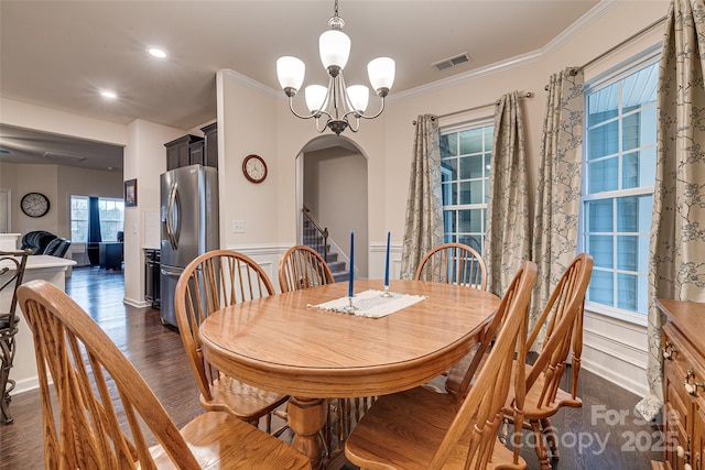 dining space featuring a notable chandelier, ornamental molding, and dark wood-type flooring