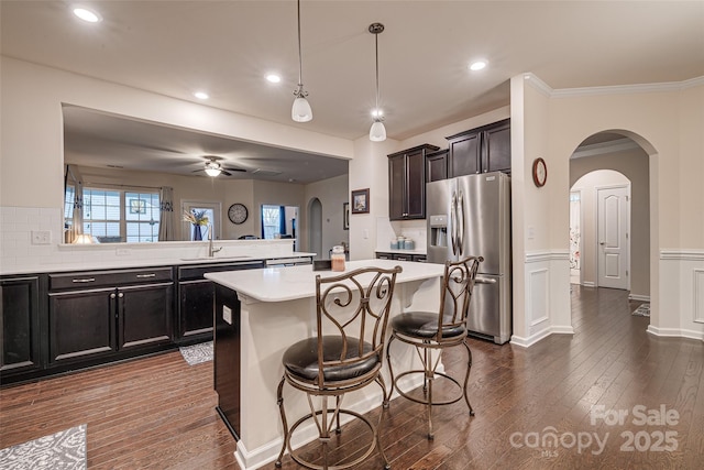 kitchen featuring a kitchen bar, stainless steel fridge, sink, pendant lighting, and a center island