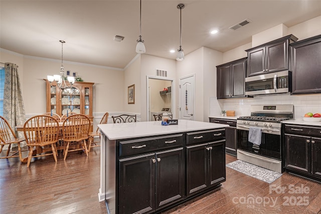 kitchen featuring stainless steel appliances, an inviting chandelier, pendant lighting, decorative backsplash, and a kitchen island