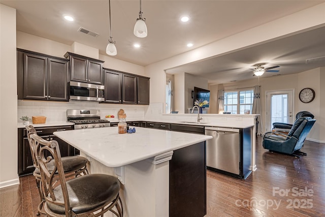 kitchen featuring kitchen peninsula, decorative light fixtures, a center island, and stainless steel appliances