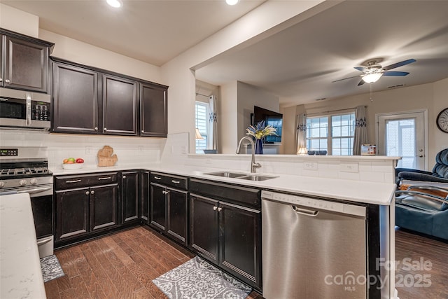 kitchen with ceiling fan, sink, stainless steel appliances, backsplash, and kitchen peninsula