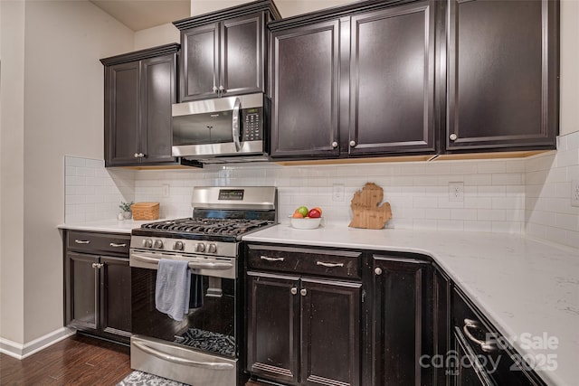 kitchen featuring decorative backsplash, appliances with stainless steel finishes, light stone counters, dark brown cabinetry, and dark hardwood / wood-style floors