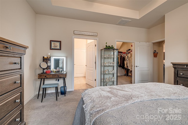 carpeted bedroom featuring a walk in closet, a raised ceiling, and a closet