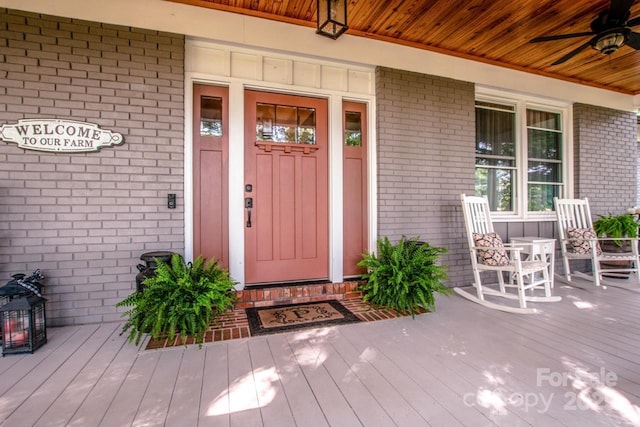 view of exterior entry featuring a porch and ceiling fan