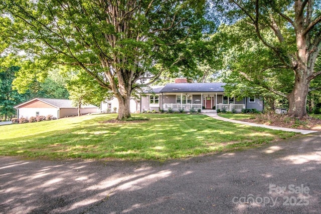 ranch-style house featuring covered porch and a front yard