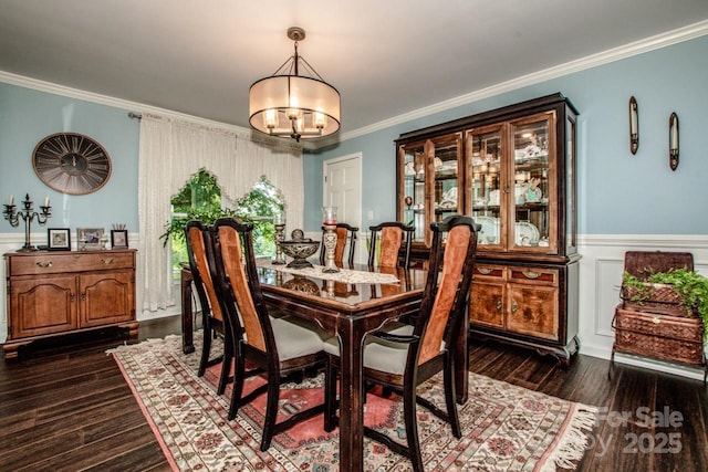 dining area with dark wood-type flooring, a notable chandelier, and ornamental molding