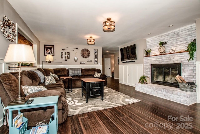 living room with dark wood-type flooring and a brick fireplace