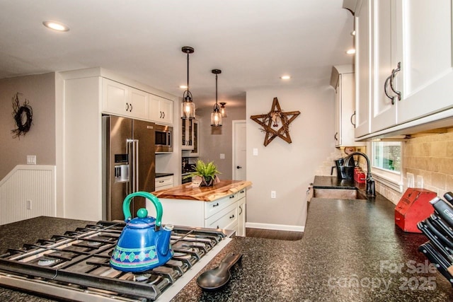 kitchen featuring wood counters, white cabinets, sink, appliances with stainless steel finishes, and tasteful backsplash