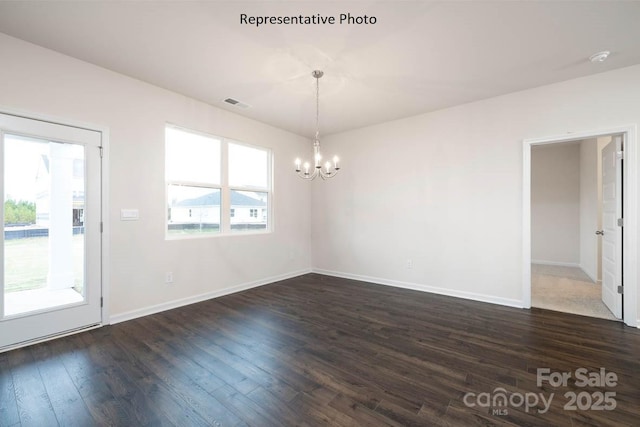 spare room featuring dark hardwood / wood-style floors, plenty of natural light, and a chandelier