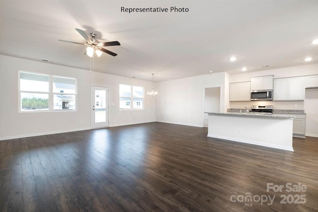 unfurnished living room with dark hardwood / wood-style floors and ceiling fan with notable chandelier