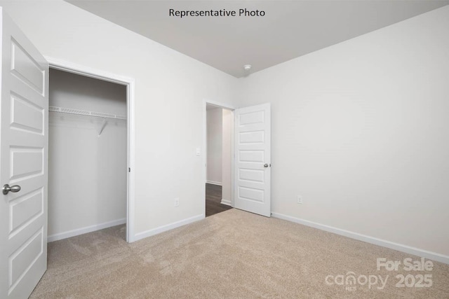 unfurnished bedroom featuring light colored carpet and a closet