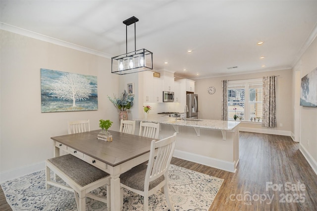 dining space featuring crown molding, dark hardwood / wood-style floors, and sink