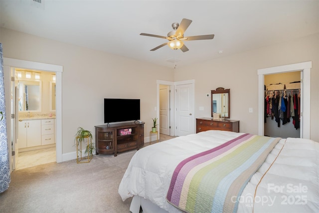 bedroom with ceiling fan, ensuite bathroom, a walk in closet, light colored carpet, and a closet