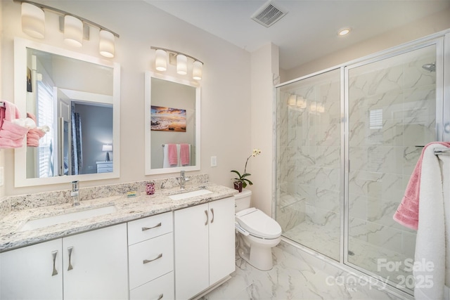 bathroom featuring vanity, a shower with shower door, and toilet