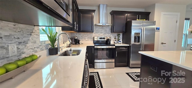 kitchen featuring tasteful backsplash, stainless steel appliances, sink, wall chimney range hood, and light tile patterned floors