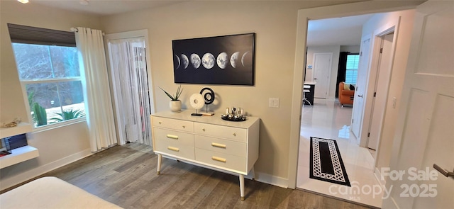 hall featuring wood finished floors, a wealth of natural light, and baseboards