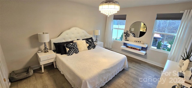 bedroom with a notable chandelier, baseboards, and wood finished floors