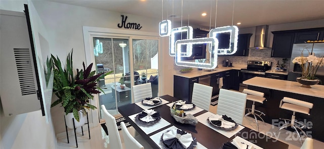 kitchen with tasteful backsplash, wall chimney exhaust hood, pendant lighting, and appliances with stainless steel finishes