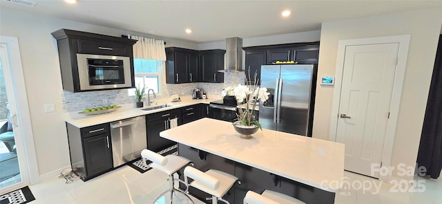 kitchen with a kitchen breakfast bar, stainless steel appliances, sink, wall chimney range hood, and light tile patterned flooring