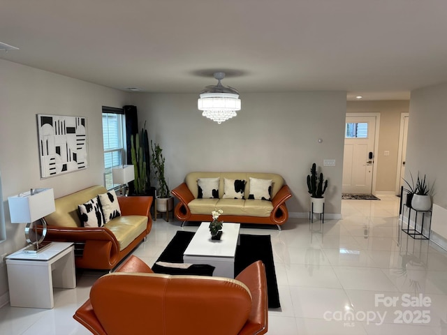 living area with a chandelier, light tile patterned floors, and baseboards