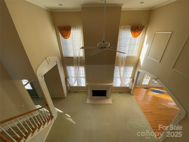 unfurnished living room featuring a wealth of natural light, crown molding, and ceiling fan