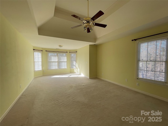 carpeted spare room with a raised ceiling, ceiling fan, a healthy amount of sunlight, and lofted ceiling