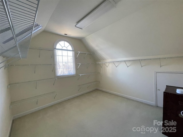 walk in closet featuring light colored carpet and vaulted ceiling