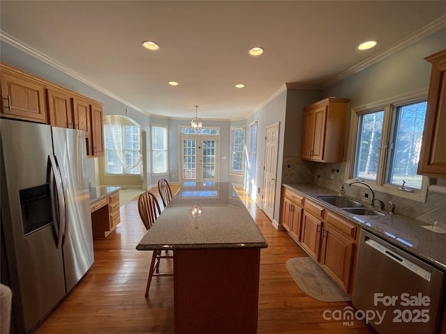 kitchen with a center island, sink, appliances with stainless steel finishes, tasteful backsplash, and a kitchen bar