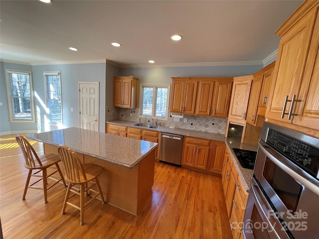 kitchen with sink, appliances with stainless steel finishes, tasteful backsplash, a kitchen island, and a kitchen bar