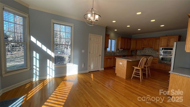 kitchen featuring double oven, backsplash, light hardwood / wood-style floors, decorative light fixtures, and a kitchen island