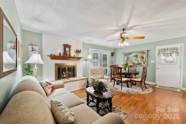 living room featuring hardwood / wood-style flooring, ceiling fan, crown molding, and a textured ceiling