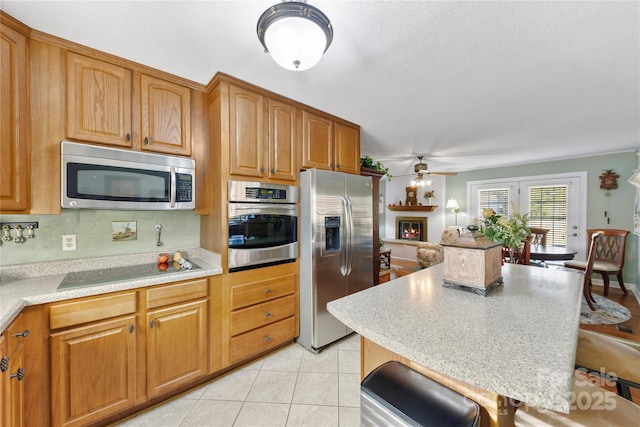 kitchen featuring ceiling fan, light tile patterned flooring, appliances with stainless steel finishes, and tasteful backsplash