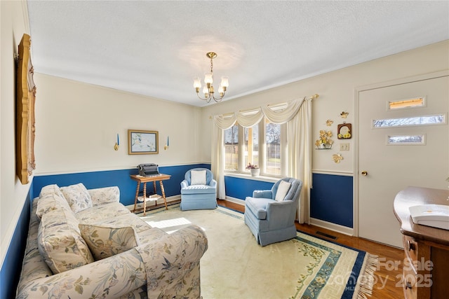 living area featuring a textured ceiling, hardwood / wood-style flooring, and an inviting chandelier