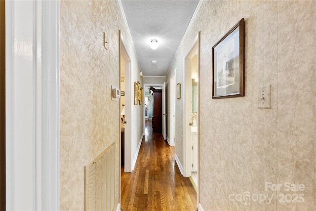 hallway featuring crown molding, a textured ceiling, and hardwood / wood-style flooring