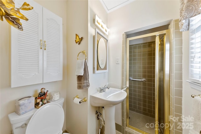 bathroom with ornamental molding, toilet, a shower with shower door, and sink