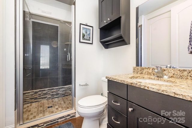 bathroom featuring vanity, a shower with shower door, and toilet