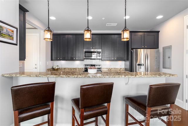 2338 Yadkin Ave Unit 505, Charlotte, NC 28205 - kitchen with stainless steel appliances, a kitchen bar, light stone counters, decorative backsplash, and electric panel