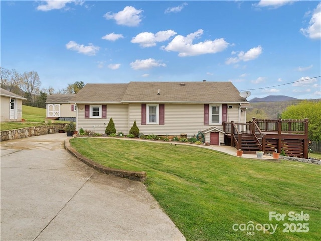 view of front of property featuring a front lawn and a deck with mountain view