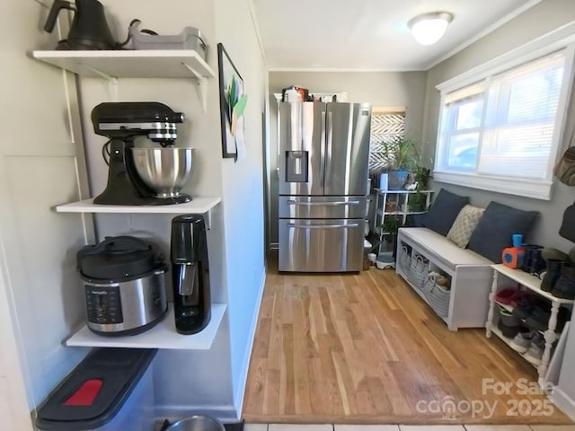 kitchen with ornamental molding, stainless steel refrigerator with ice dispenser, and light hardwood / wood-style flooring