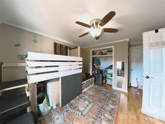 bedroom featuring wood-type flooring, a closet, ceiling fan, and ornamental molding