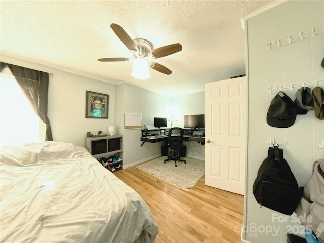 bedroom featuring ceiling fan, wood-type flooring, and a textured ceiling