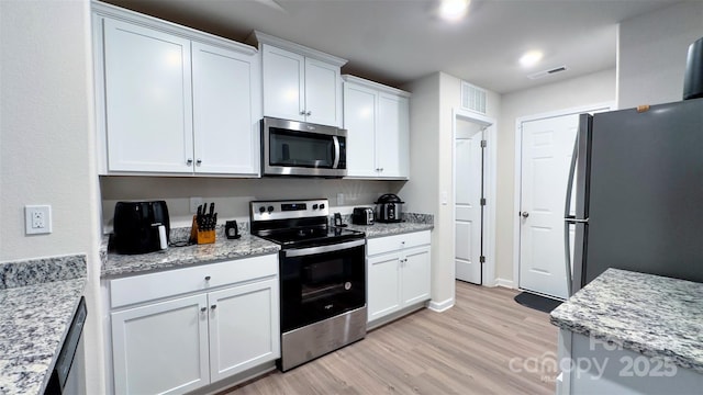 kitchen with white cabinetry, light hardwood / wood-style flooring, stainless steel appliances, and light stone counters