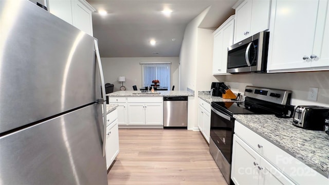 kitchen with white cabinets, sink, light hardwood / wood-style flooring, appliances with stainless steel finishes, and light stone counters