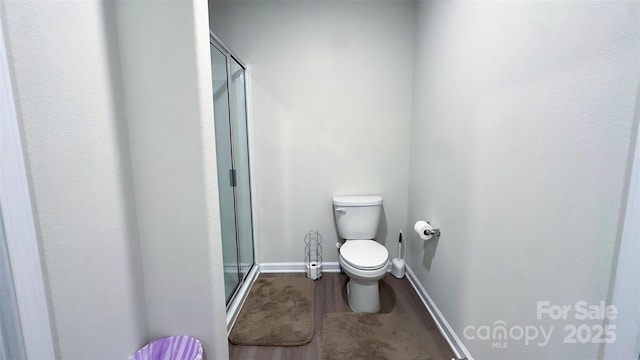 bathroom featuring hardwood / wood-style floors, toilet, and a shower with shower door