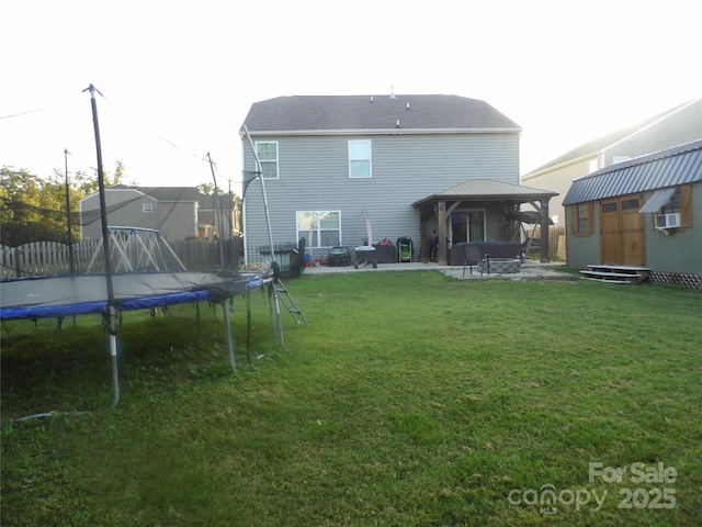 rear view of house with a lawn, a trampoline, a storage shed, a gazebo, and a patio area