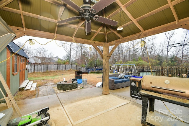 view of patio / terrace with ceiling fan, an outdoor fire pit, a grill, a trampoline, and a gazebo